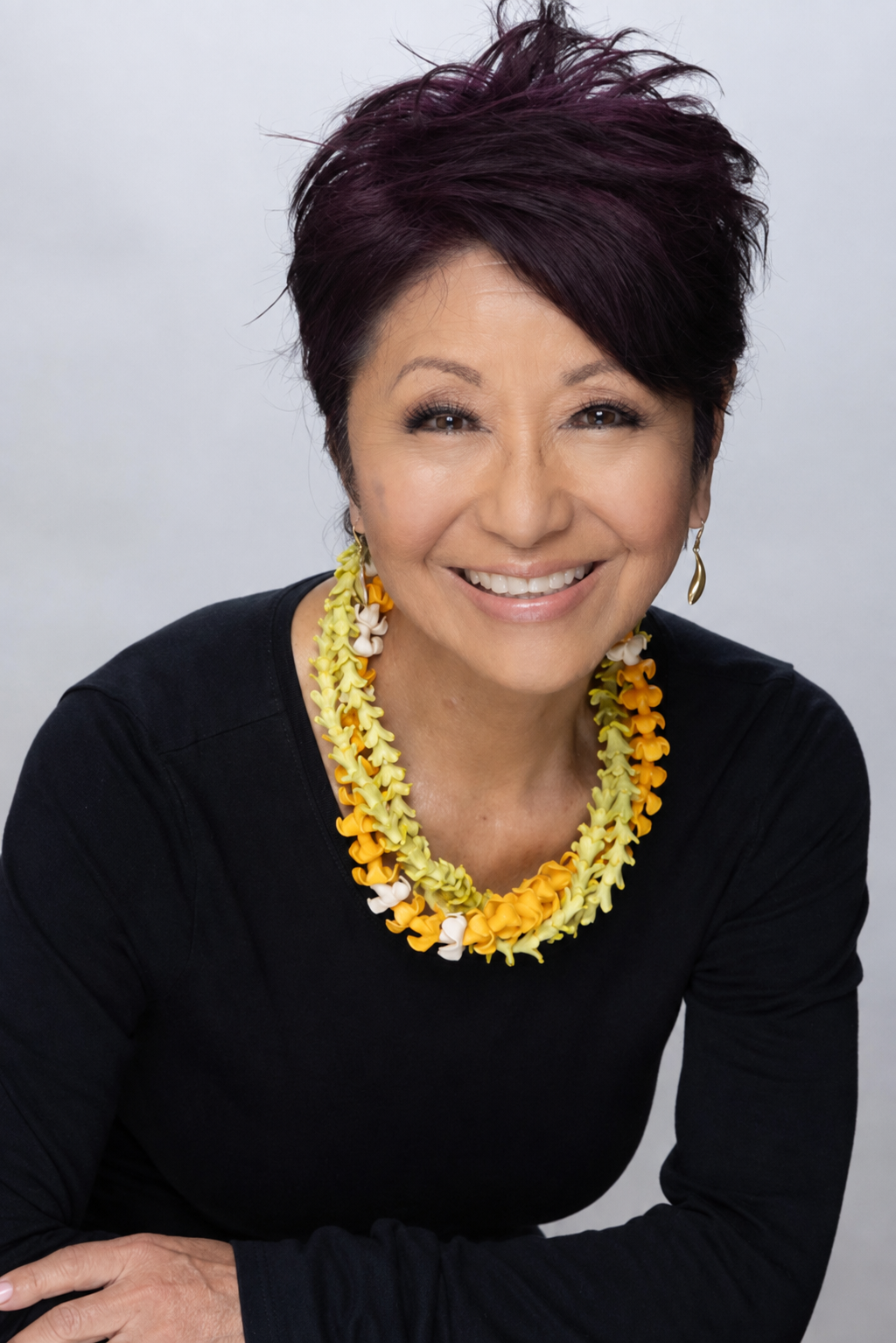 Olelo pa'a Ogawa, founder of Glow Hawaii, smiling warmly wearing a golden lei